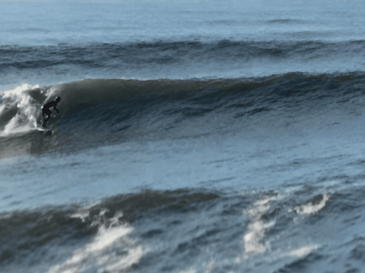 A surfer riding a breaking wave at Rick's Beach